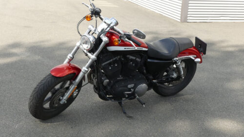 En röd och vit Harley-Davidson 1200 Custom cruiser-motorcykel parkerad utomhus